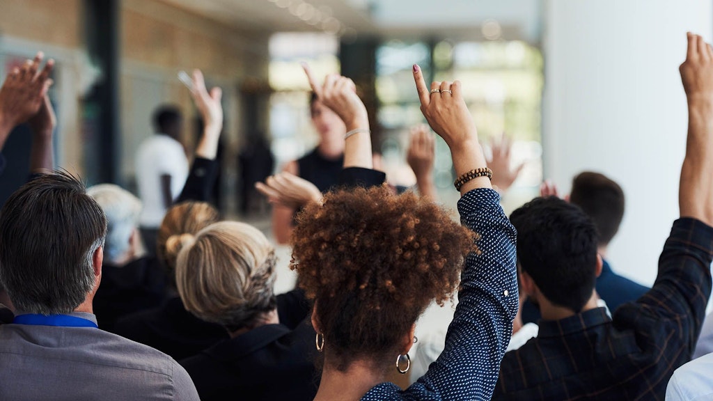 Un groupe de personnes levant les mains pendant une conférence.