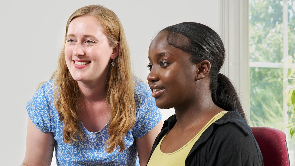 Zwei junge Menschen in Ausbildung arbeiten vor einem Bildschirm.