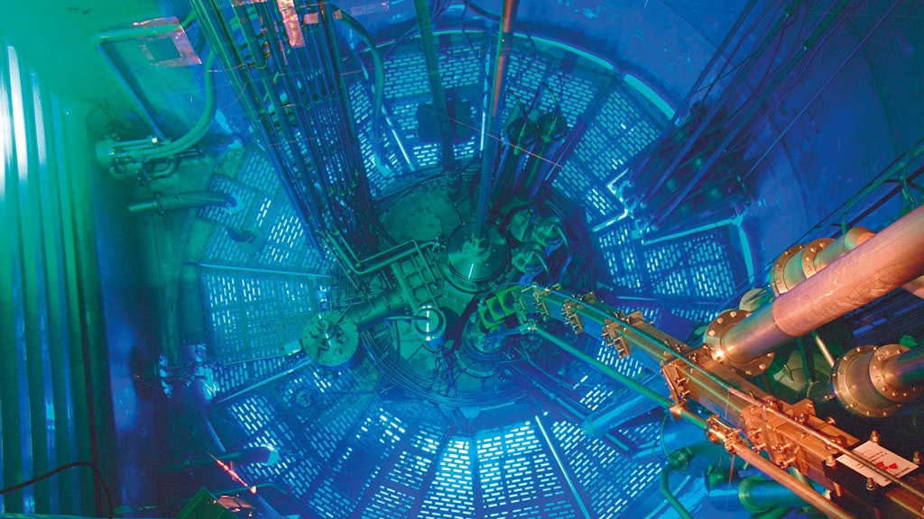 Blick in das Innere einer hochkomplexen technischen Anlage mit zahlreichen Rohren, Kabeln und Metallstrukturen, blau beleuchtet.