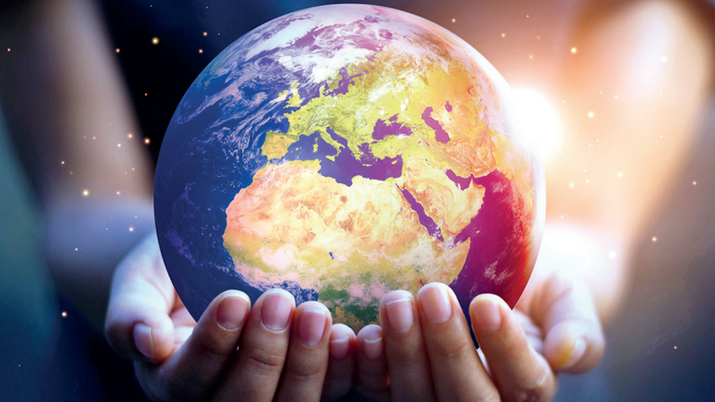 Two hands holding a colourful depiction of the Earth against a dark background.