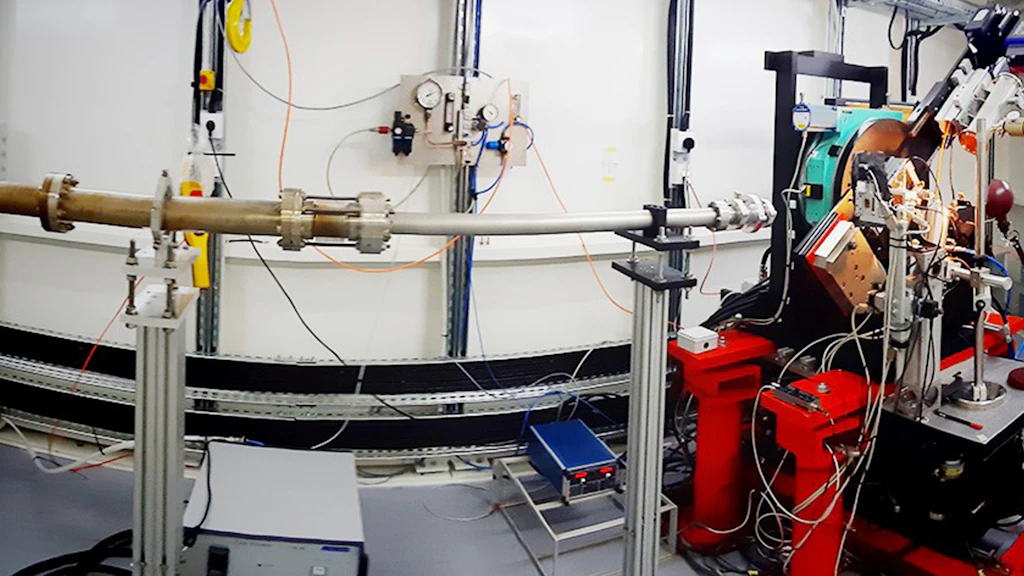 Installation de laboratoire technique avec des tubes métalliques, des instruments de mesure et un dispositif expérimental monté sur des supports rouges et argentés.