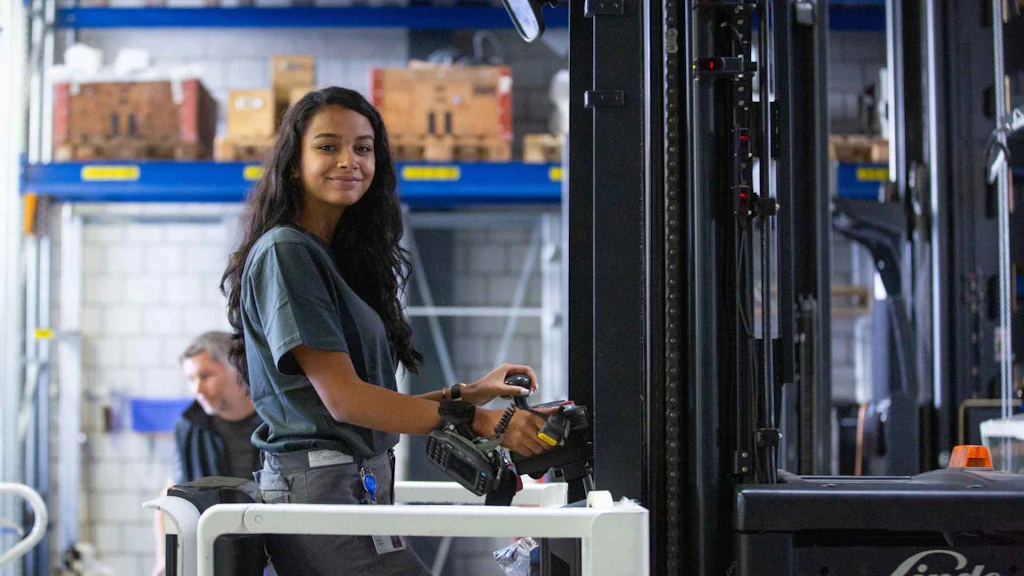 Giovane collaboratrice utilizza un carrello elevatore in un moderno magazzino